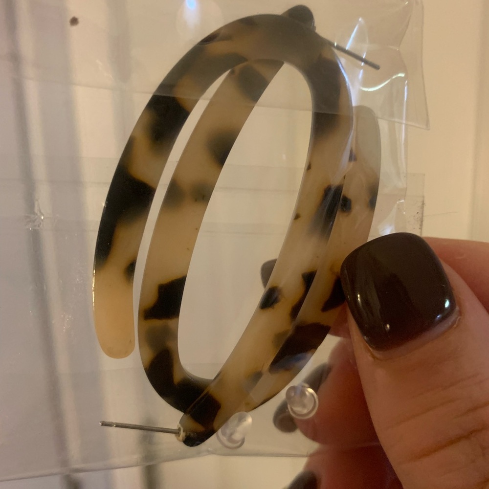 Pair of oblong hoop tortoise shell color earrings with clear backs.